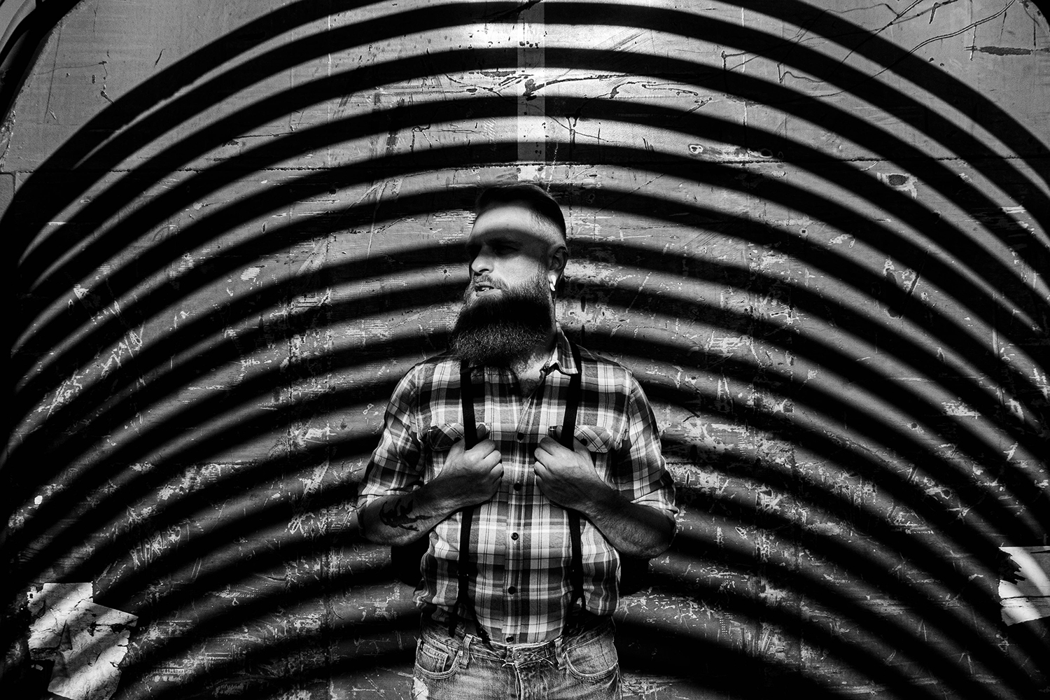 Photographie noir et blanc d'un modèle homme strié par l'ombre d'une structure de wagon