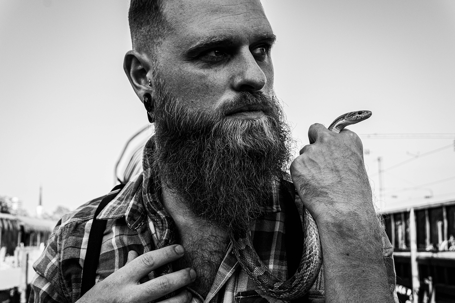 Photographie noir et blanc d'un modèle homme avec un serpent sur ses épaules et dans sa main